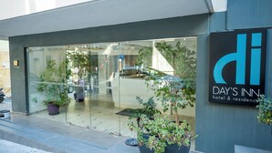 A modern building with a glass facade, a sign for 'Day's Inn hotel & residence', and potted plants in front. - Day's Inn Hotel and Residence (Sliema)