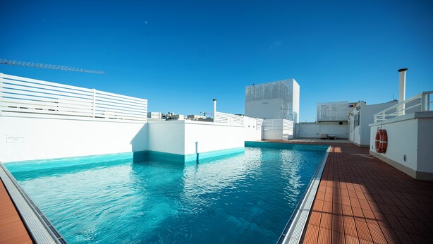 A pool area with a clear blue sky, a wooden deck, and a white railing. - Day's Inn Hotel and Residence (Sliema)