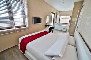 A hotel room with a bed, a TV, a bathroom with a sink and mirror, and a window with blinds. - Quaint Boutique Hotel Nadur (Nadur)