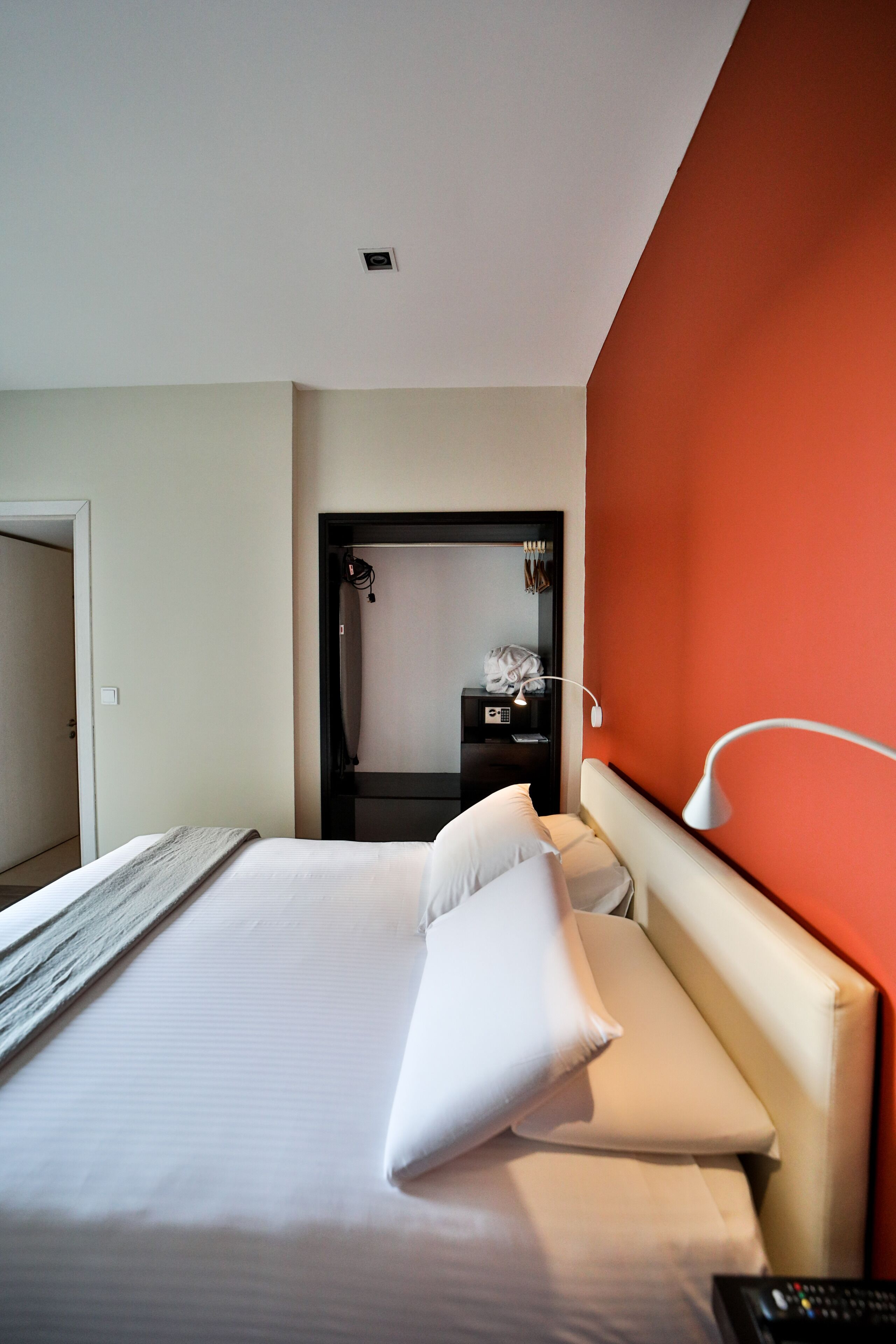 Una habitación de hotel con cama, mesita de noche, lámpara y espejo.