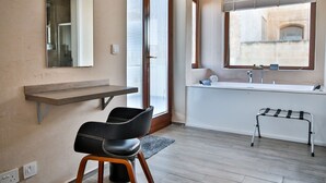 Un baño moderno con un espejo grande, un lavabo integrado y una ventana con vista a un edificio.