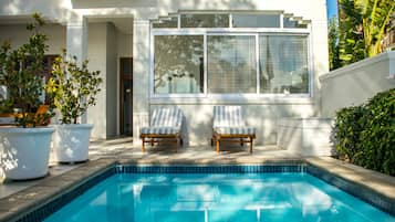 Una piscina al aire libre, sillones reclinables de piscina