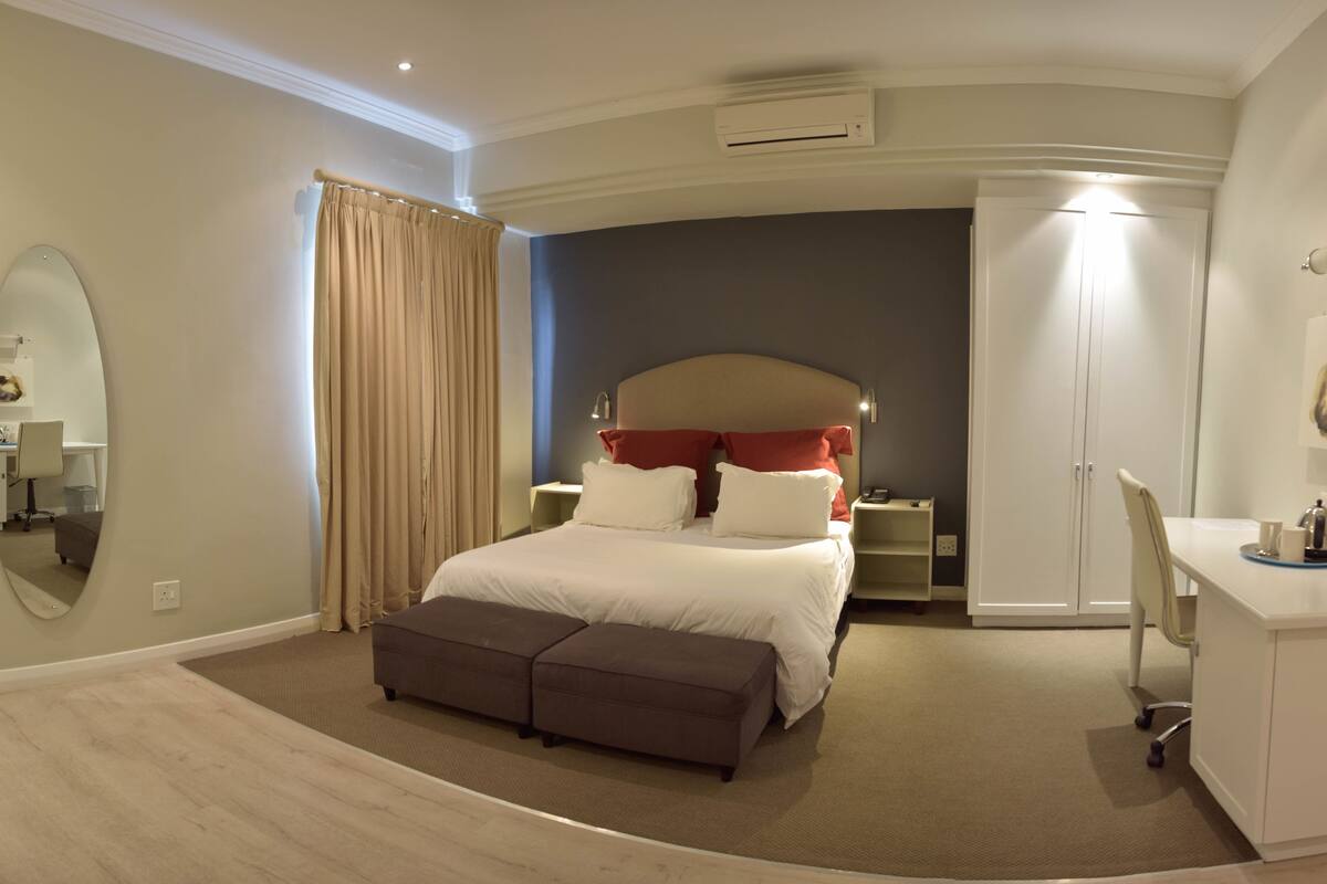 Un dormitorio con cama, escritorio, armario y espejo.
