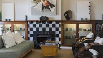 A living room with a checkered fireplace, a green sofa, a wooden coffee table, and a dark sofa with white cushions.