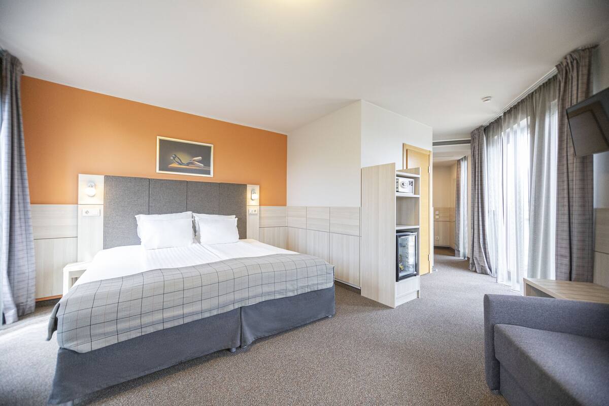 Una habitación de hotel con una cama grande, un escritorio, una silla y un televisor.