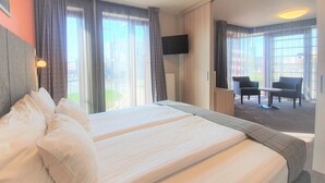 A hotel room with two beds, a TV mounted on the wall, and a view of the outdoors. - Wellton Riga Hotel & SPA (Riga)