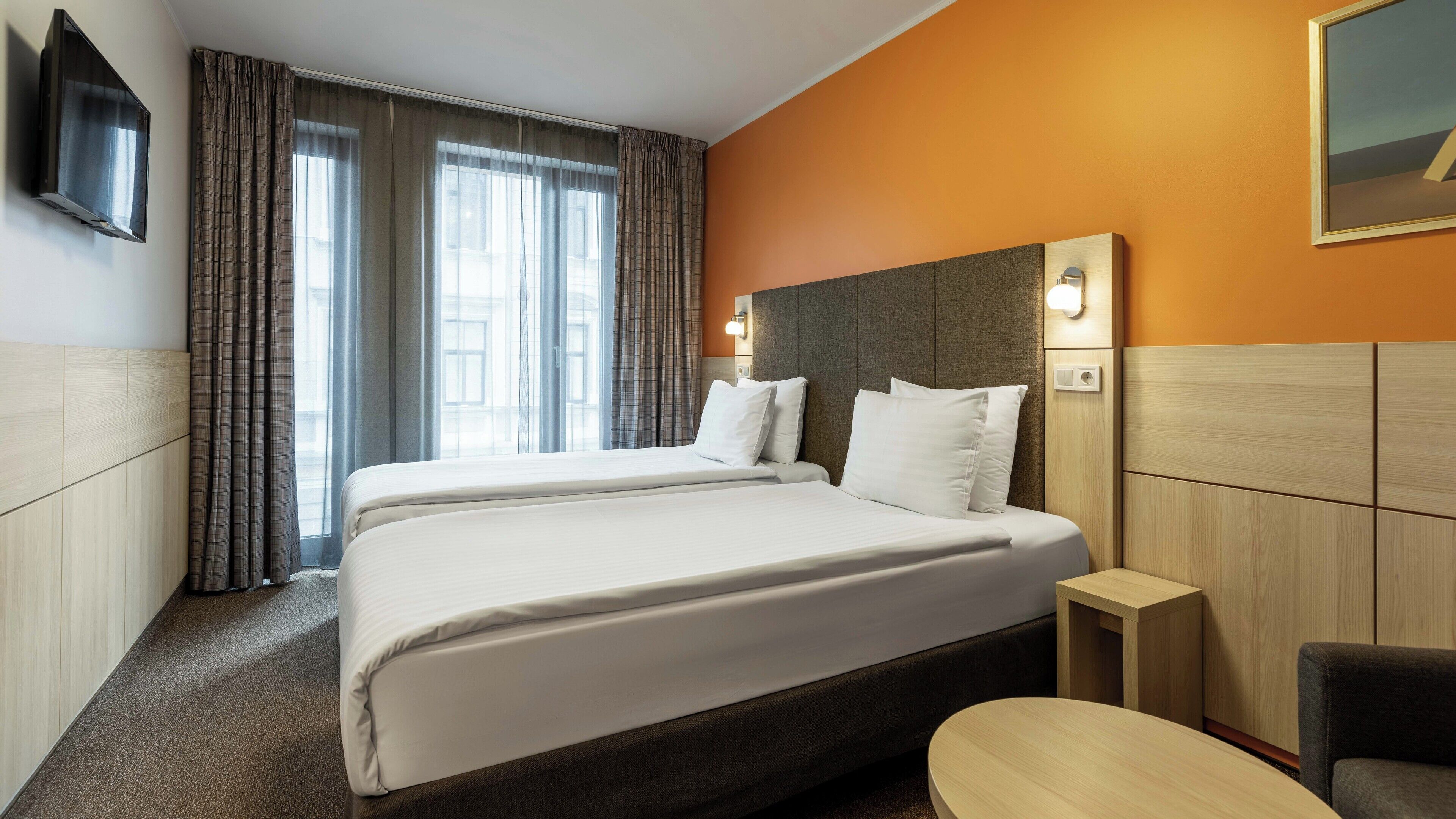 Habitación de hotel con dos camas, televisión, escritorio y una silla.