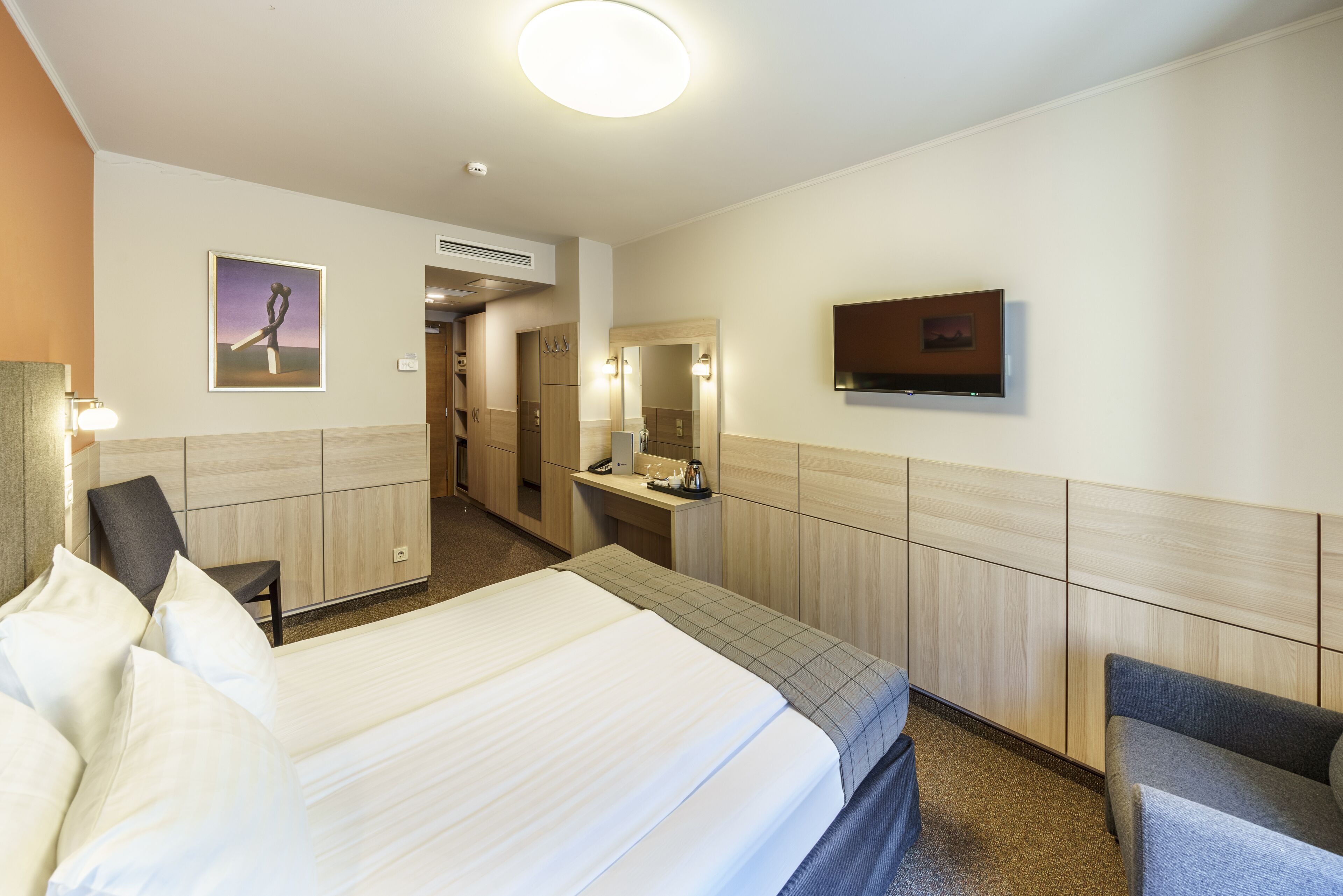 Una habitación de hotel con cama, escritorio, silla, televisor y baño.