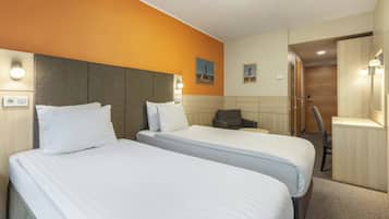 Una habitación de hotel con dos camas, un escritorio, una silla y un armario.