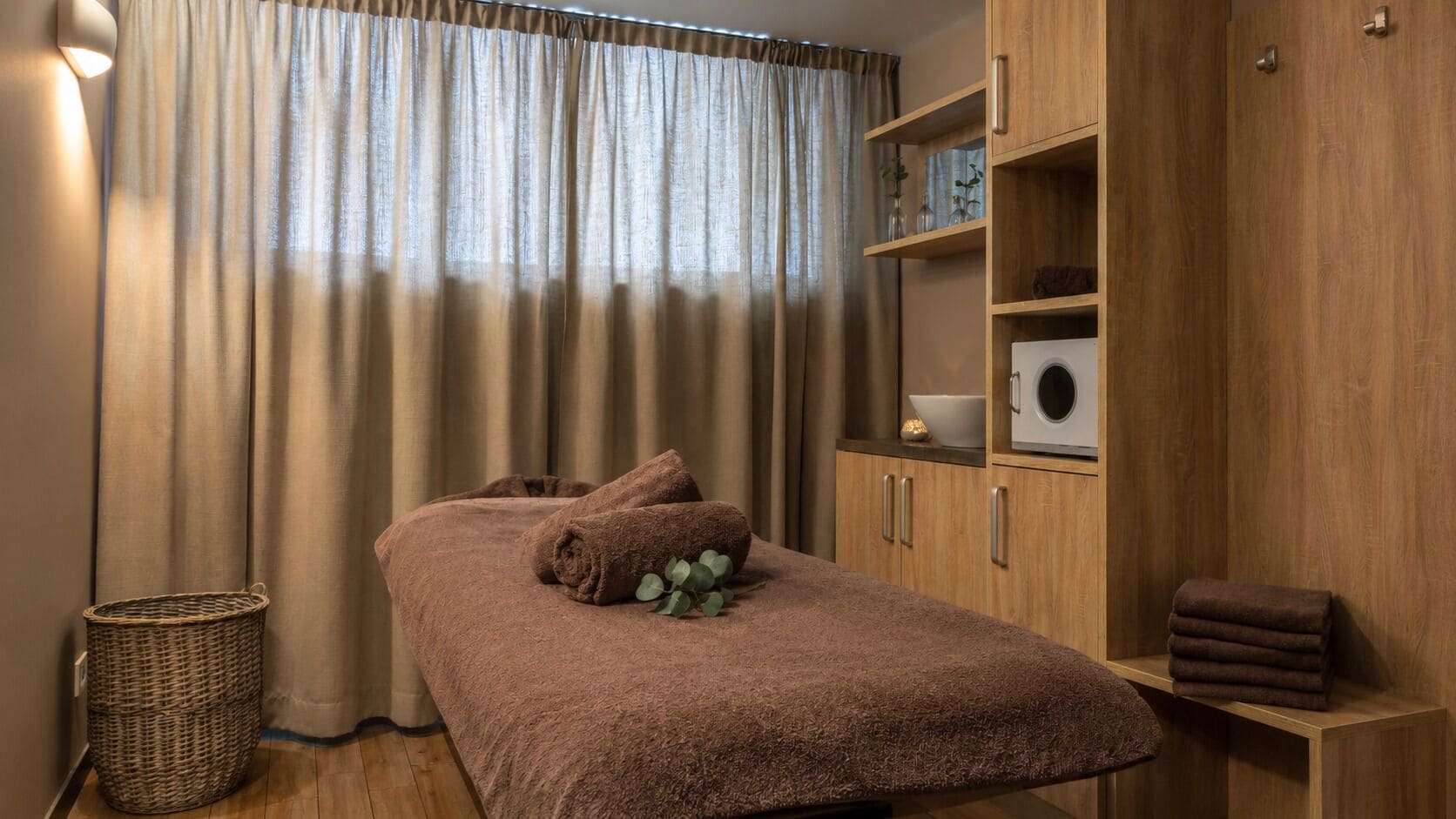Een kamer met een bed, een houten kast, een mand en een raam met gordijnen.