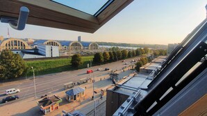 A view from a window overlooking a city street with buildings, a bridge, and a river. - Wellton Riga Hotel & SPA (Riga)