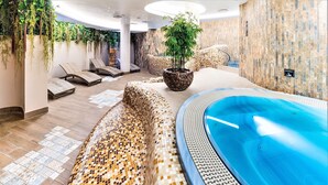 A spa area with a hot tub, lounge chairs, and a mosaic-patterned floor.