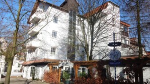 A traditional European building with a white facade, a wooden entrance canopy, and a sign indicating a beer garden. - Hotel Bürgerbräu (Osnabrueck)