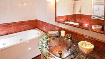 A bathroom with a bathtub, a glass sink with a decorative basin, a mirror, and a towel rack.