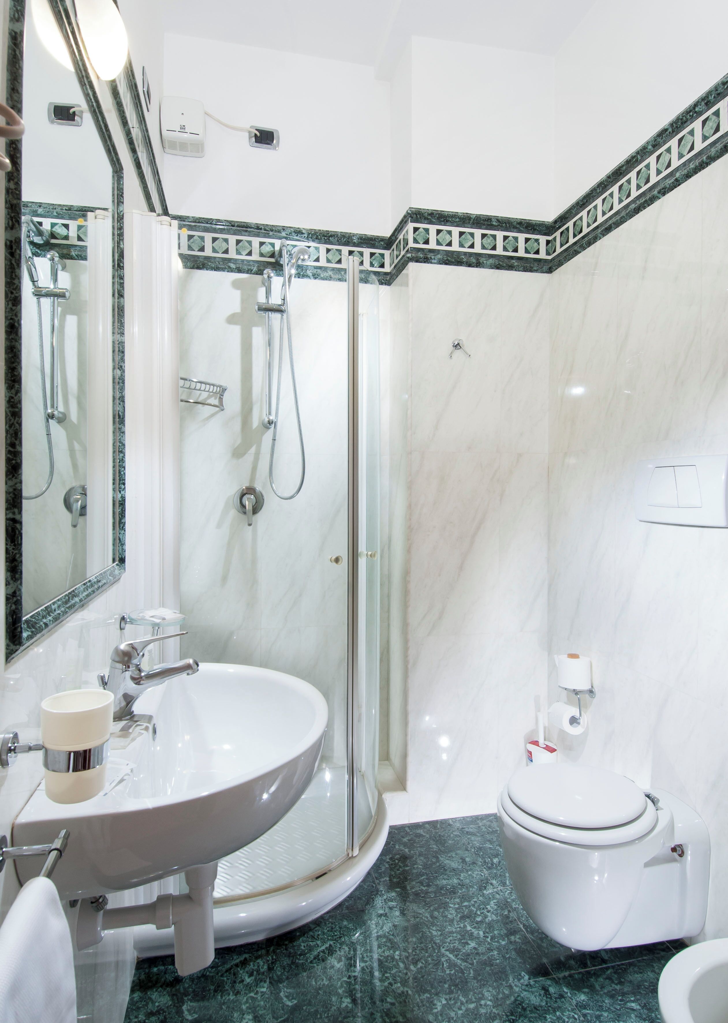 Un baño moderno con ducha envuelta en vidrio, lavamanos redondo y un inodoro.