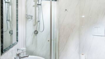 Un baño moderno con ducha envuelta en vidrio, lavamanos redondo y un inodoro.