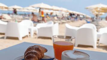 Una mesa con un croissant, un vaso de jugo de naranja y una taza de café con la etiqueta 'SAFFEE SACCARIA'.