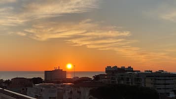 Un coucher de soleil sur un paysage urbain côtier, avec des bâtiments et un ciel dégagé.