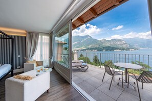 A balcony with a view of the sea and mountains, furnished with a sofa, chairs, and a table. - Borgo Le Terrazze (Bellagio)
