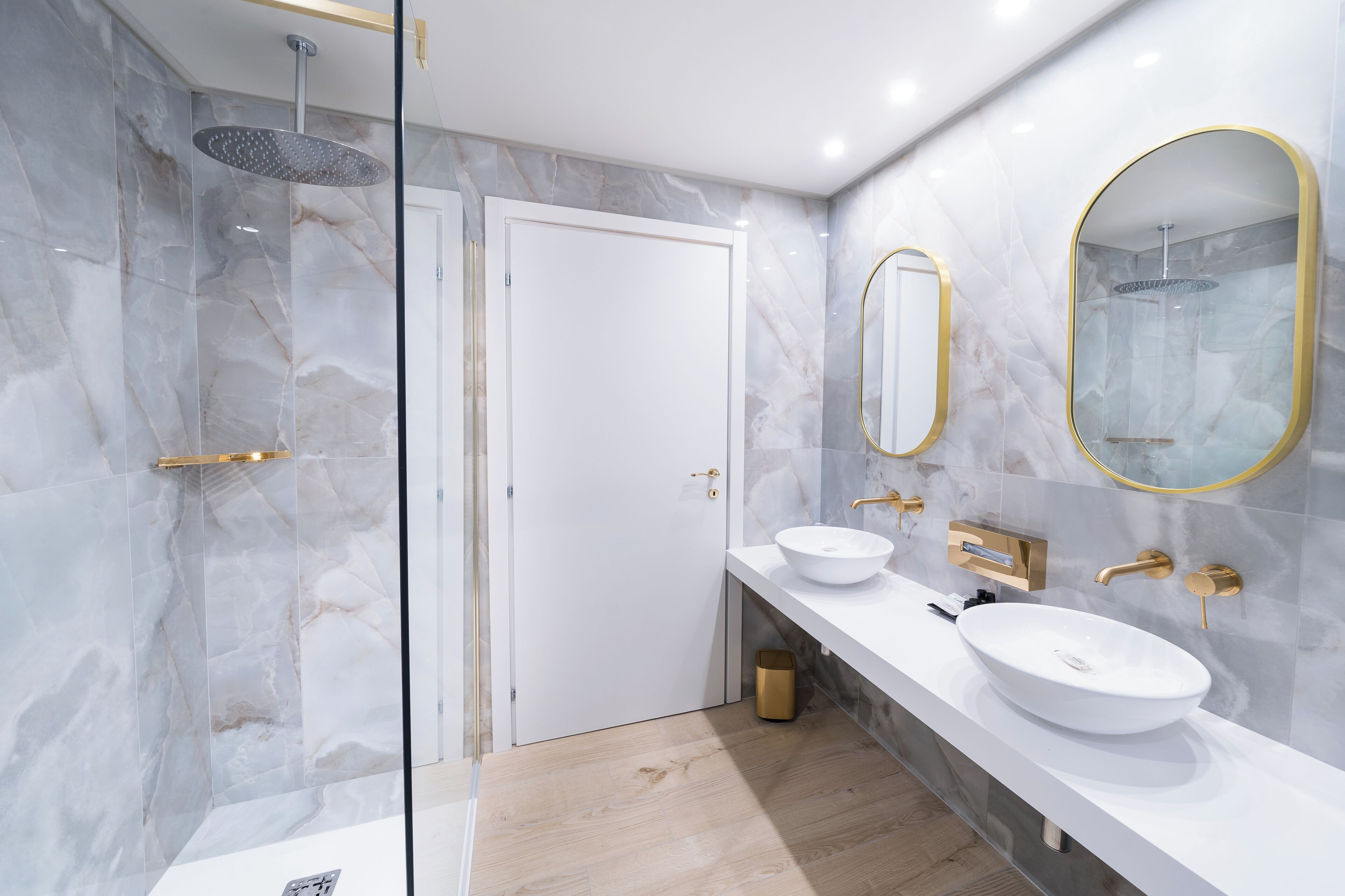 A modern bathroom with two sinks, a shower, and a glass-enclosed shower area.