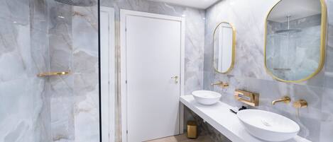 A modern bathroom with two sinks, a shower, and a glass-enclosed shower area.