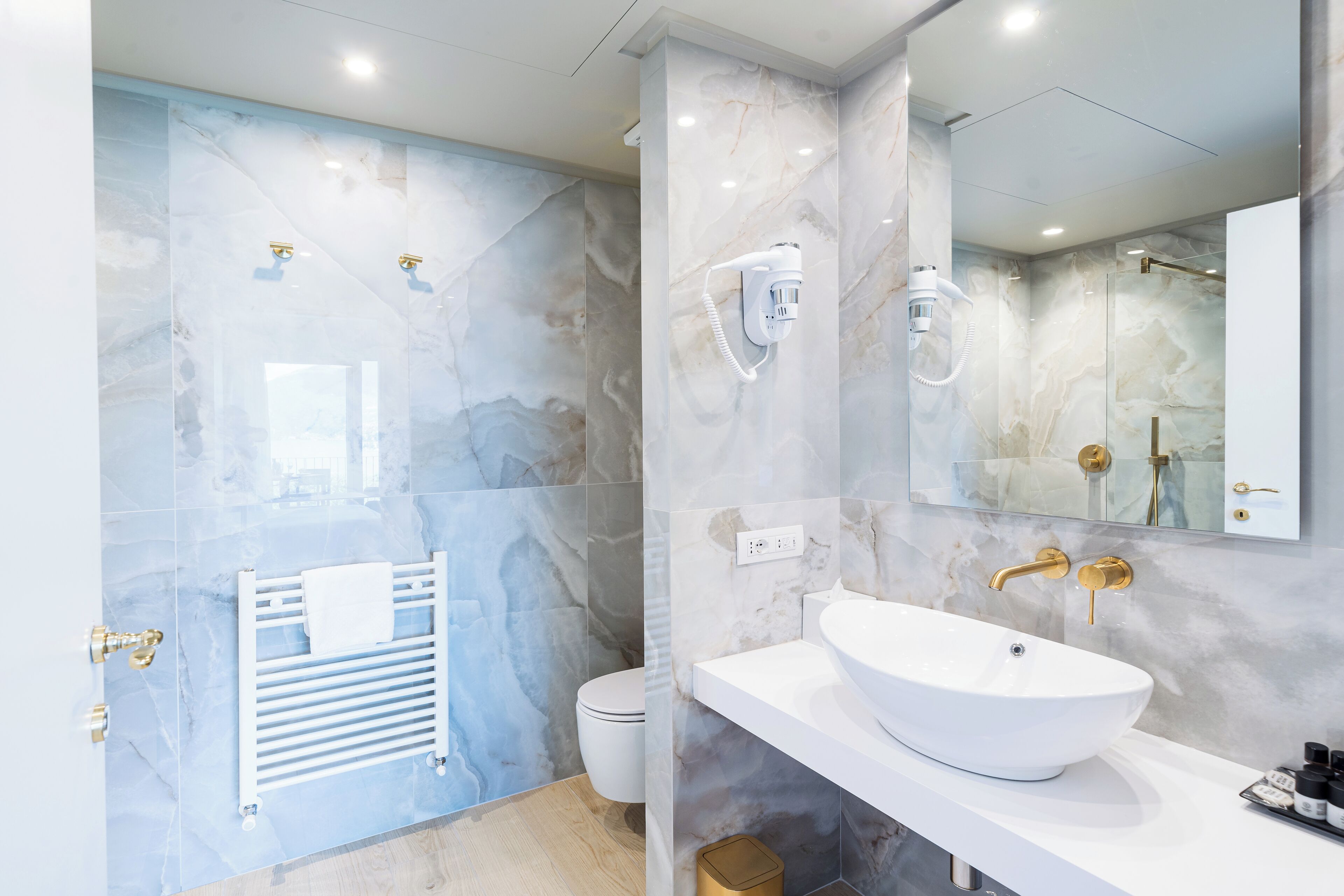 Ein modernes Badezimmer mit Waschbecken, Marmorwänden, einem Handtuchhalter und einer Toilette.