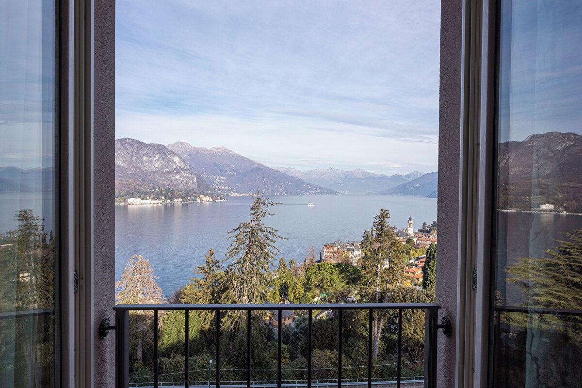 A view from a balcony overlooking a lake with mountains in the background.