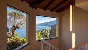 Una escalera con vistas a un árbol y un paisaje montañoso a través de amplios ventanales.