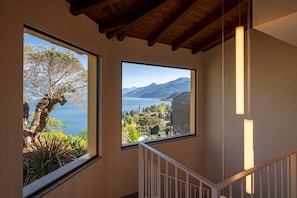 A staircase with a view of a tree and a mountain landscape through large windows. - Borgo Le Terrazze (Bellagio)