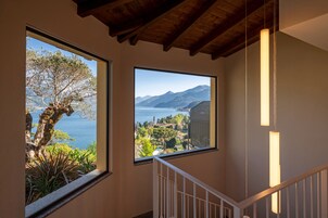 Una scala che offre vista su un albero e un paesaggio montano attraverso ampie finestre.