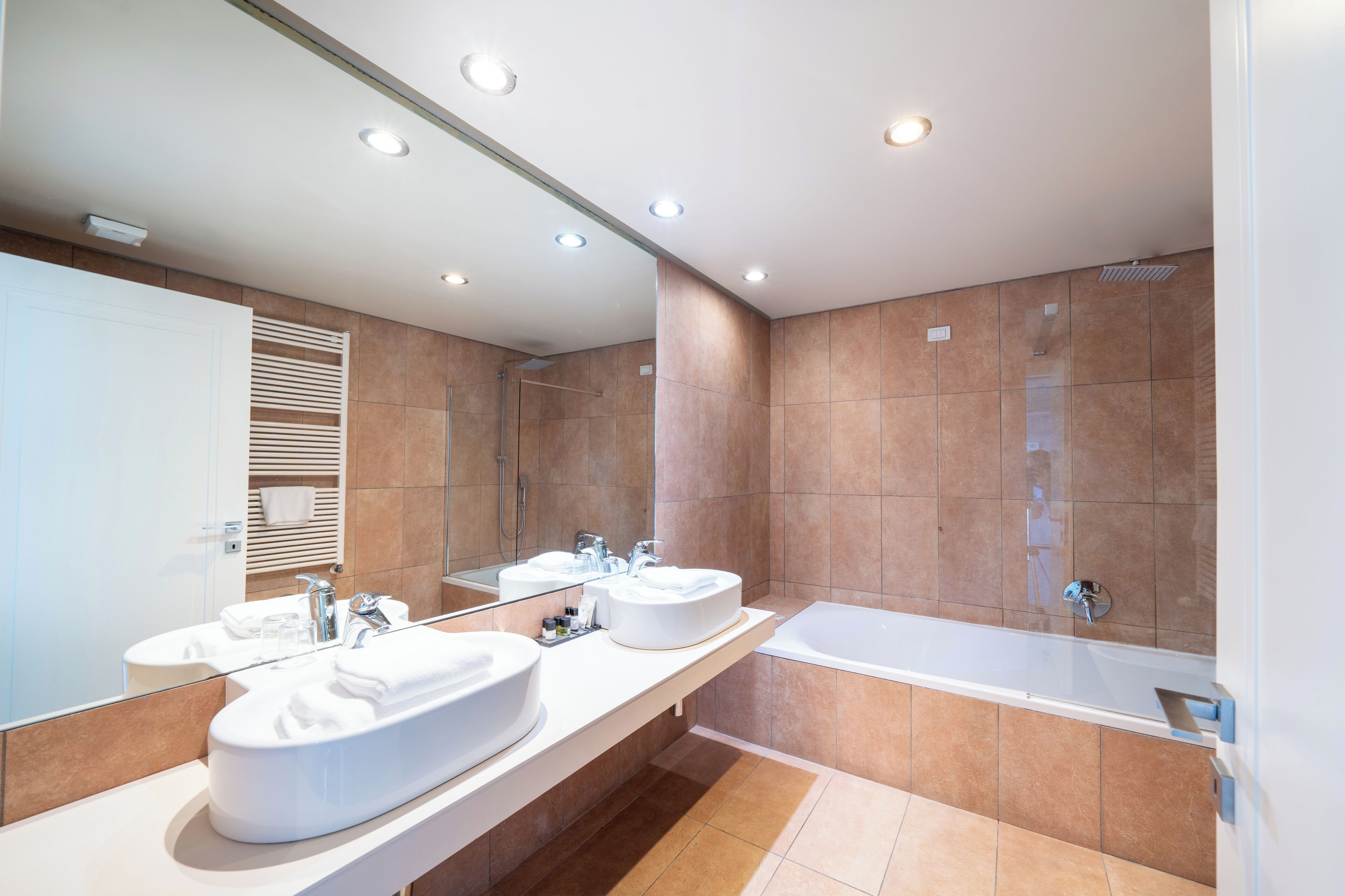 Un baño moderno con dos lavamanos, un espejo grande y una bañera.
