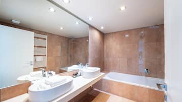Un baño moderno con dos lavamanos, un espejo grande y una bañera.