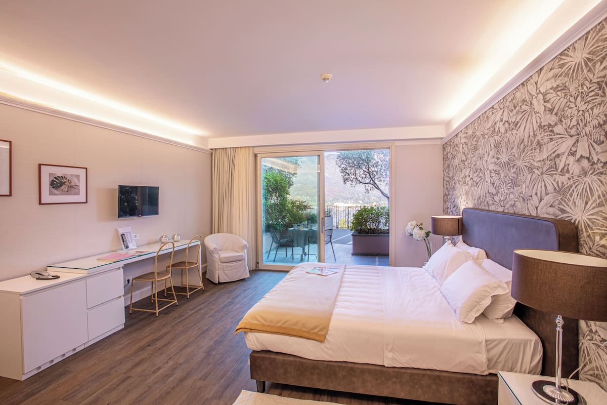A hotel room with a bed, desk, chair, and a view of the outdoors.
