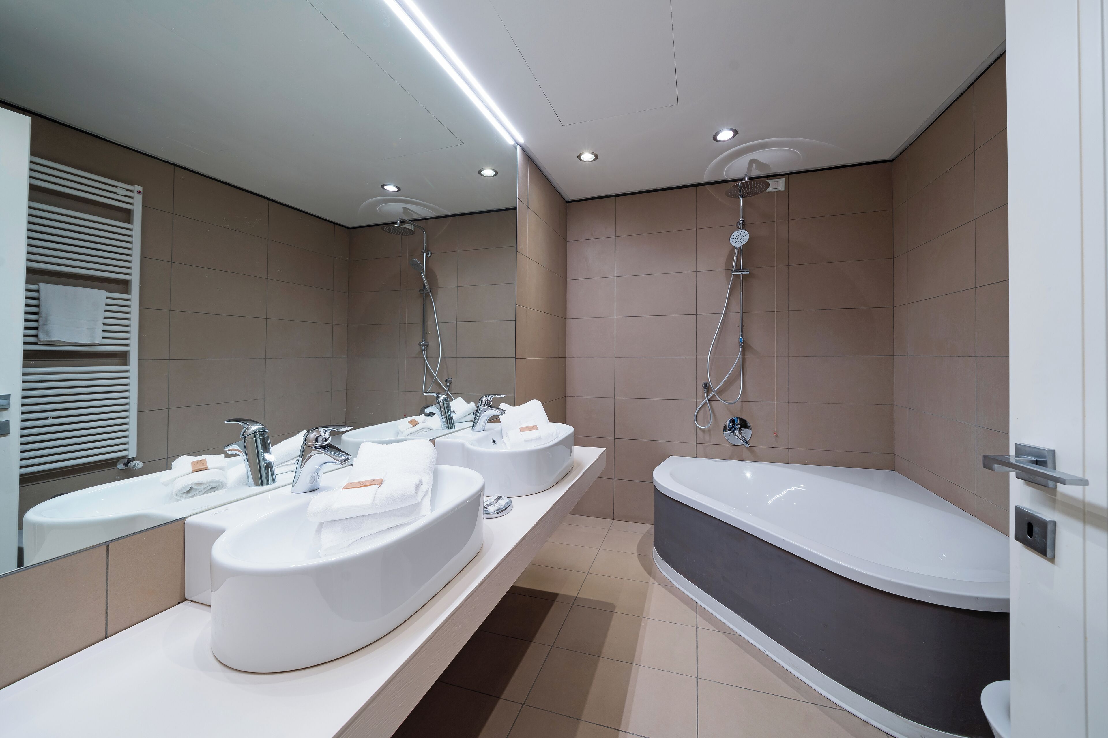 Un baño moderno con dos lavamanos, una bañera y una ducha.