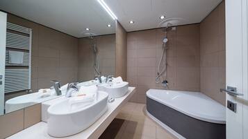A modern bathroom with two sinks, a bathtub, and a shower.