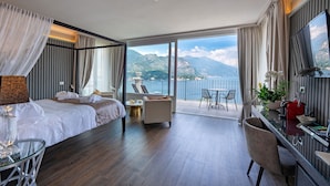 Una habitación de hotel con una cama grande, una zona de estar con vistas a la montaña y un balcón con mesa y sillas.