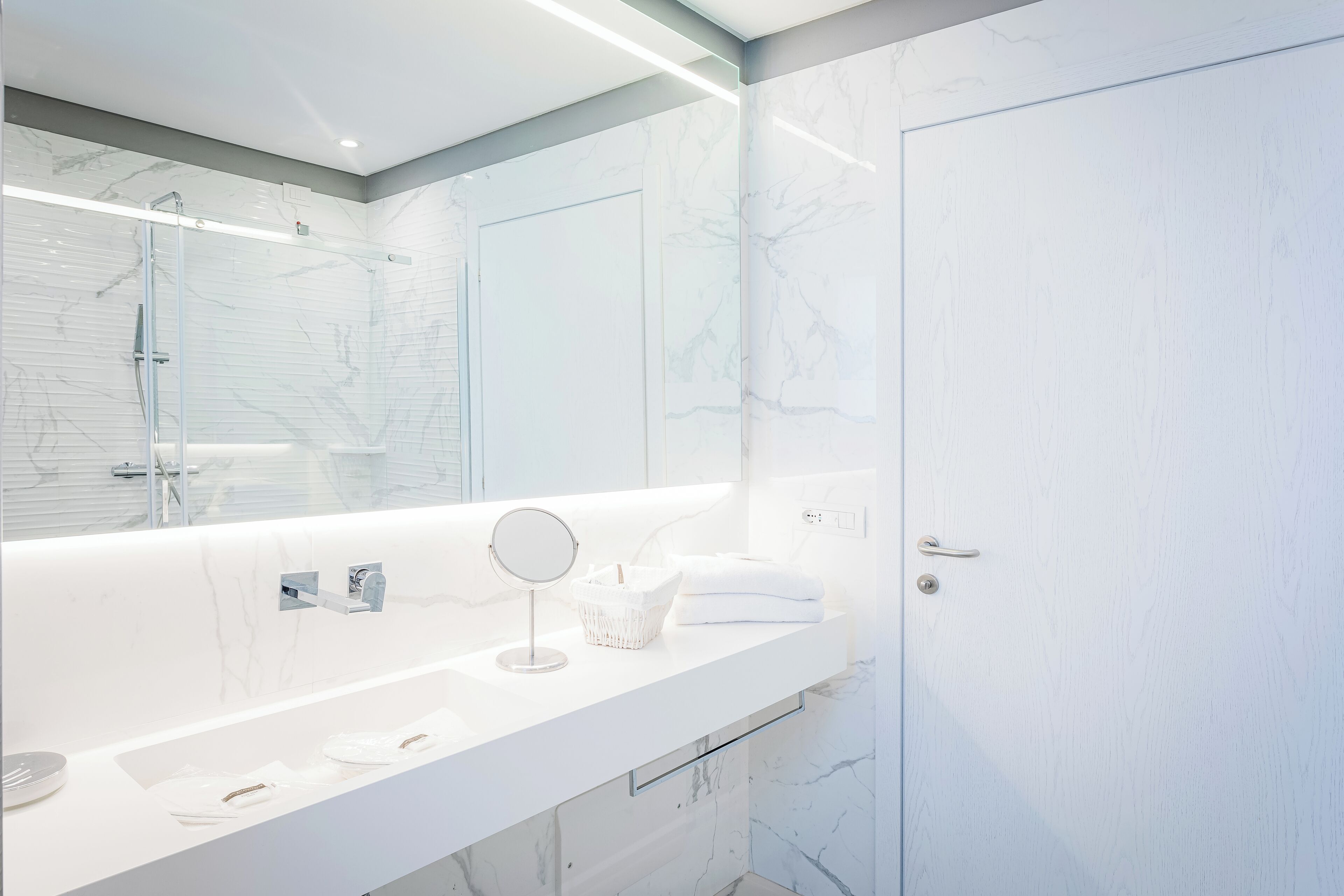 A modern bathroom with a large mirror, a sink, and a shower area.