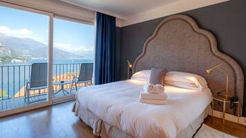 Ein Schlafzimmer mit einem großen Bett, Meerblick und einem Balkon mit Stühlen.