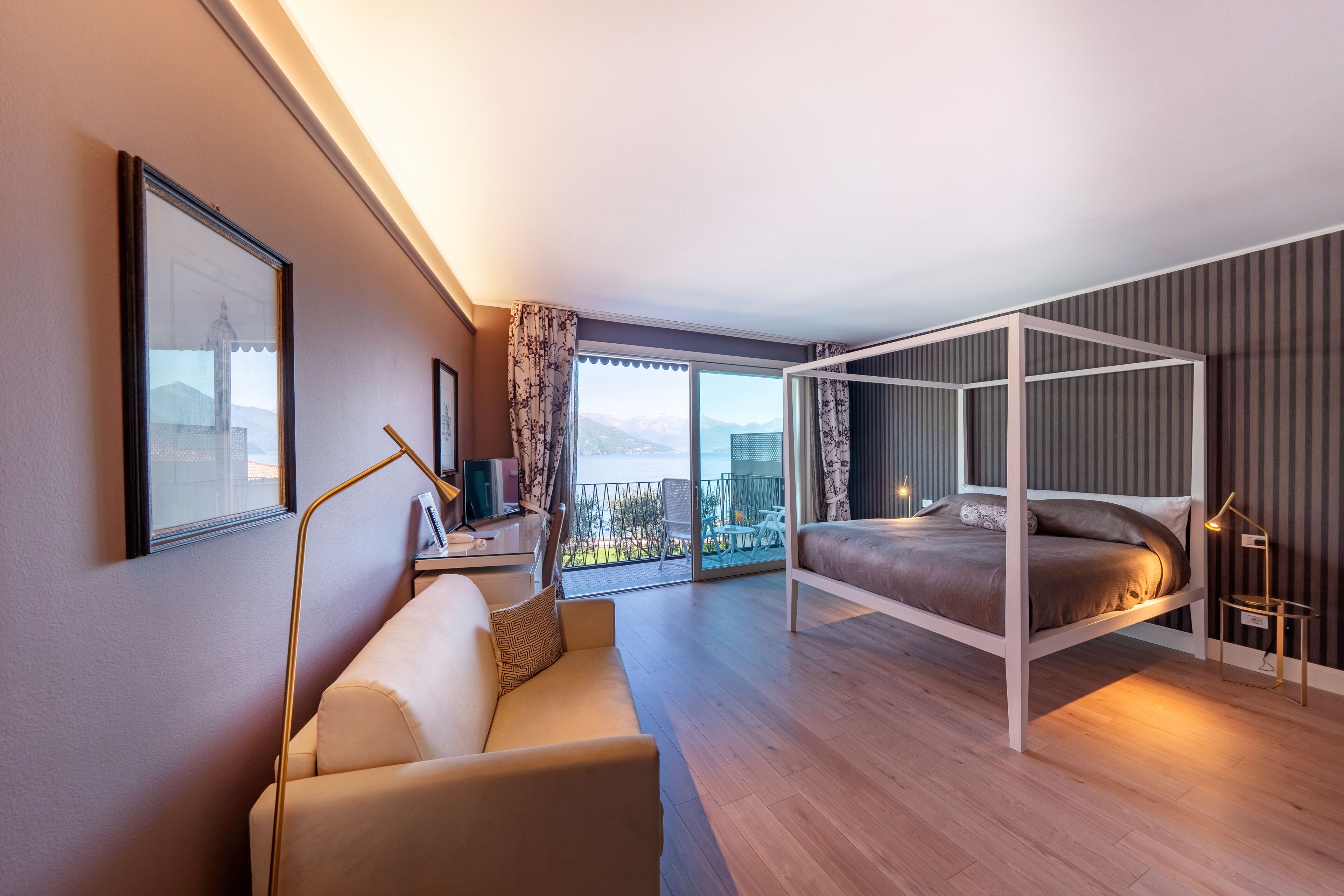 Una habitación de hotel moderna con balcón, cama, sofá y escritorio.
