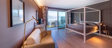 Una habitación de hotel moderna con balcón, cama, sofá y escritorio.