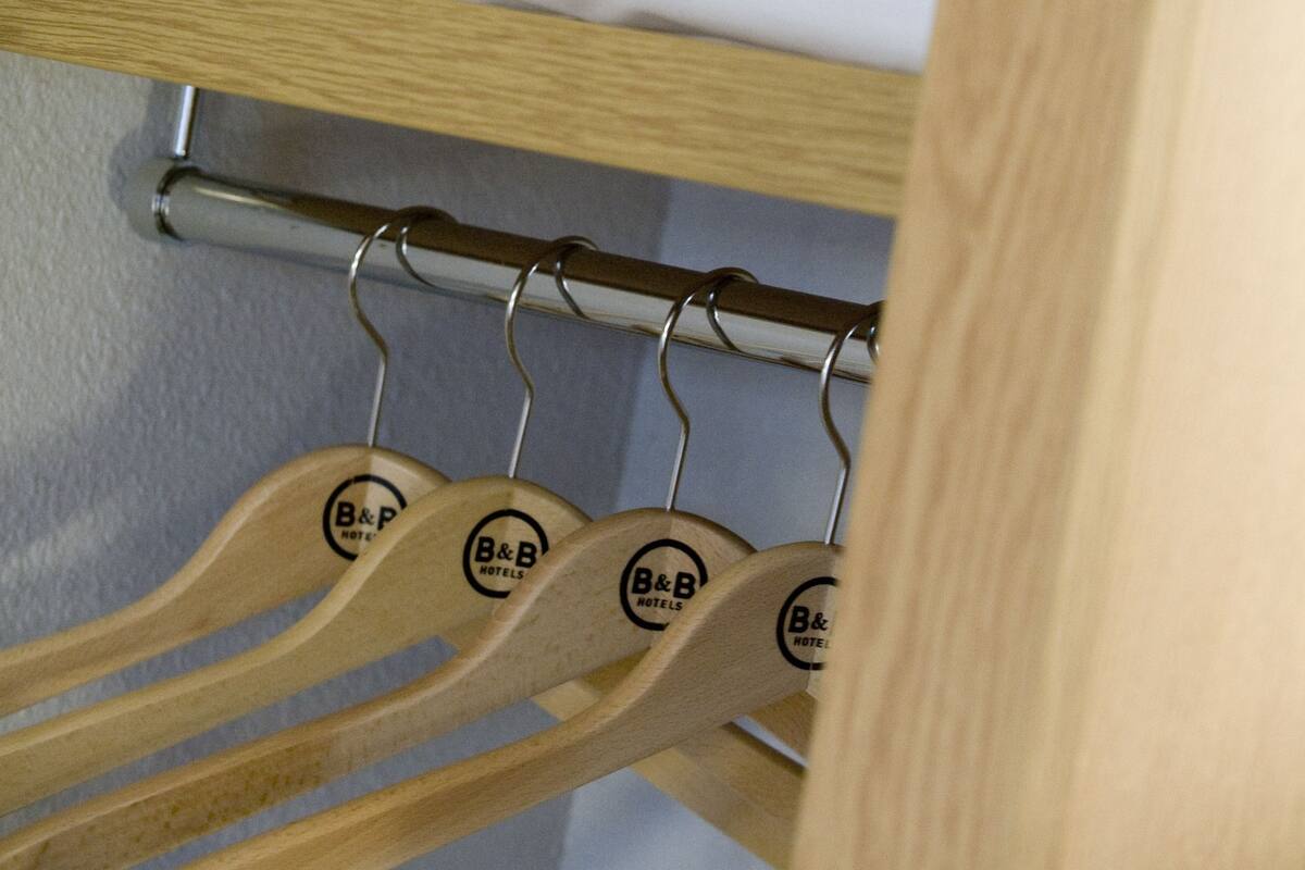 Ein Hotelzimmer mit einem aufgeräumten Bett, einem Handtuch und Holzaufhängern mit dem Hotel-Logo.