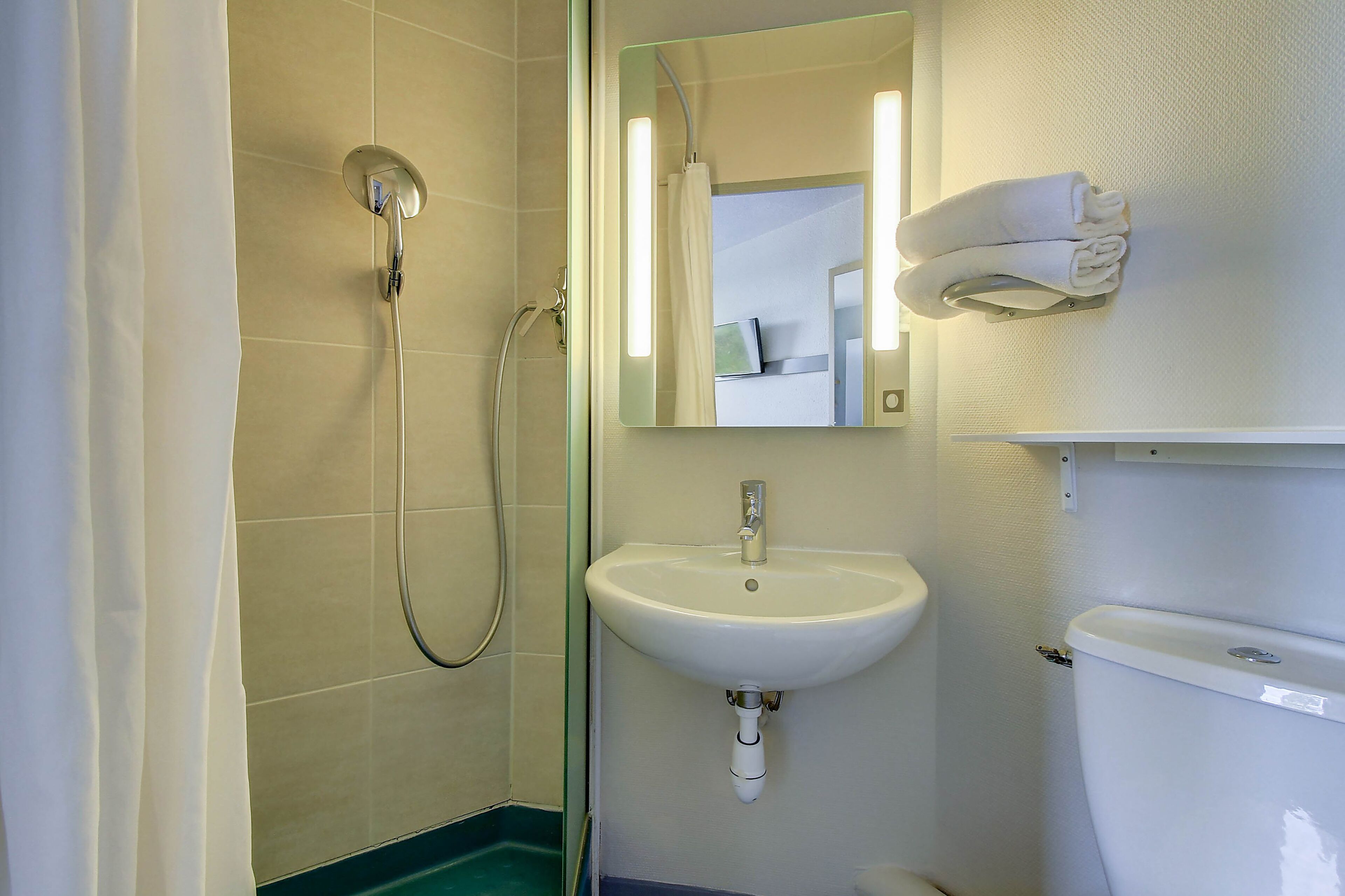 Een badkamer met douche, wastafel en toilet.