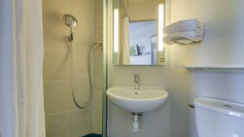 Een badkamer met douche, wastafel en toilet.