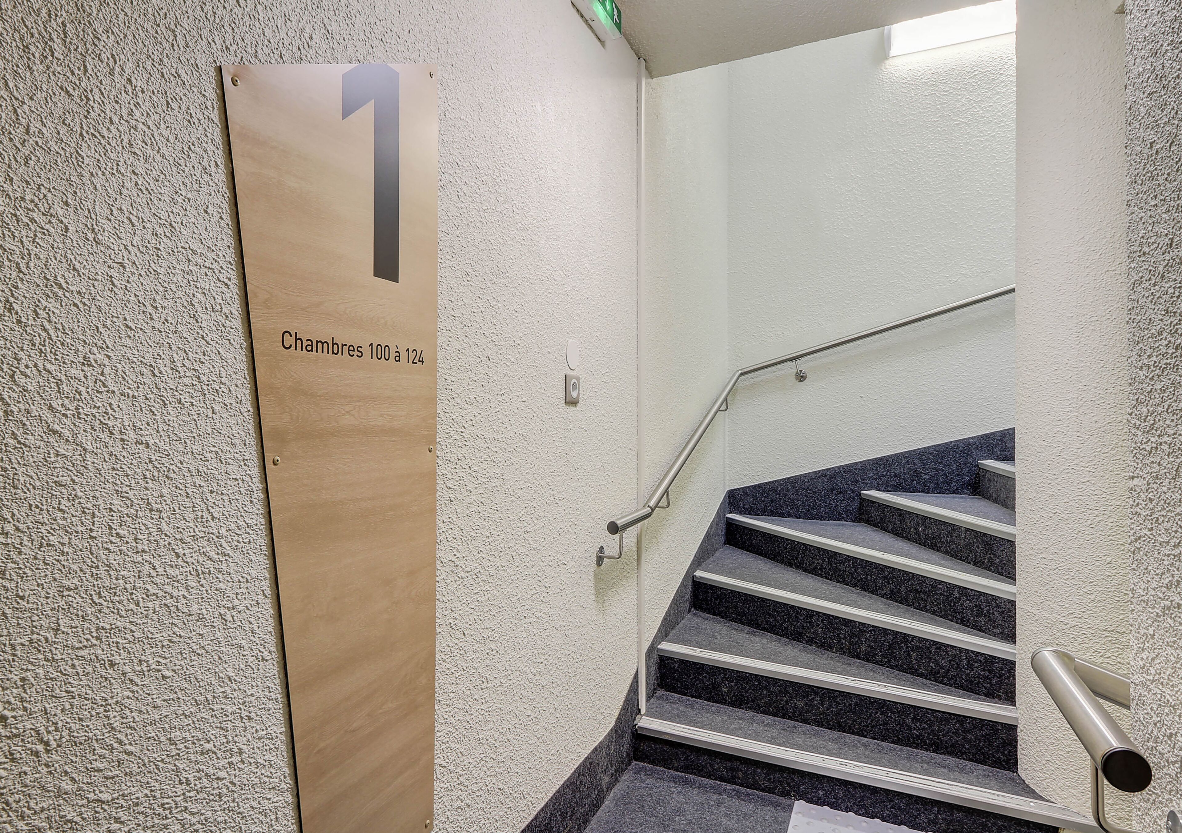 Un escalier muni d’une rampe et d’une indication signalant le numéro de la pièce : 1.