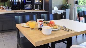 Una mesa de desayuno con un croissant, jugo de naranja, una taza de café y un plato de comida.