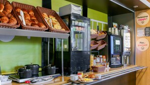 A breakfast buffet with bread, pastries, and coffee machines. - B&B HOTEL Fréjus Roquebrune-sur-Argens (Roquebrune-sur-Argens)