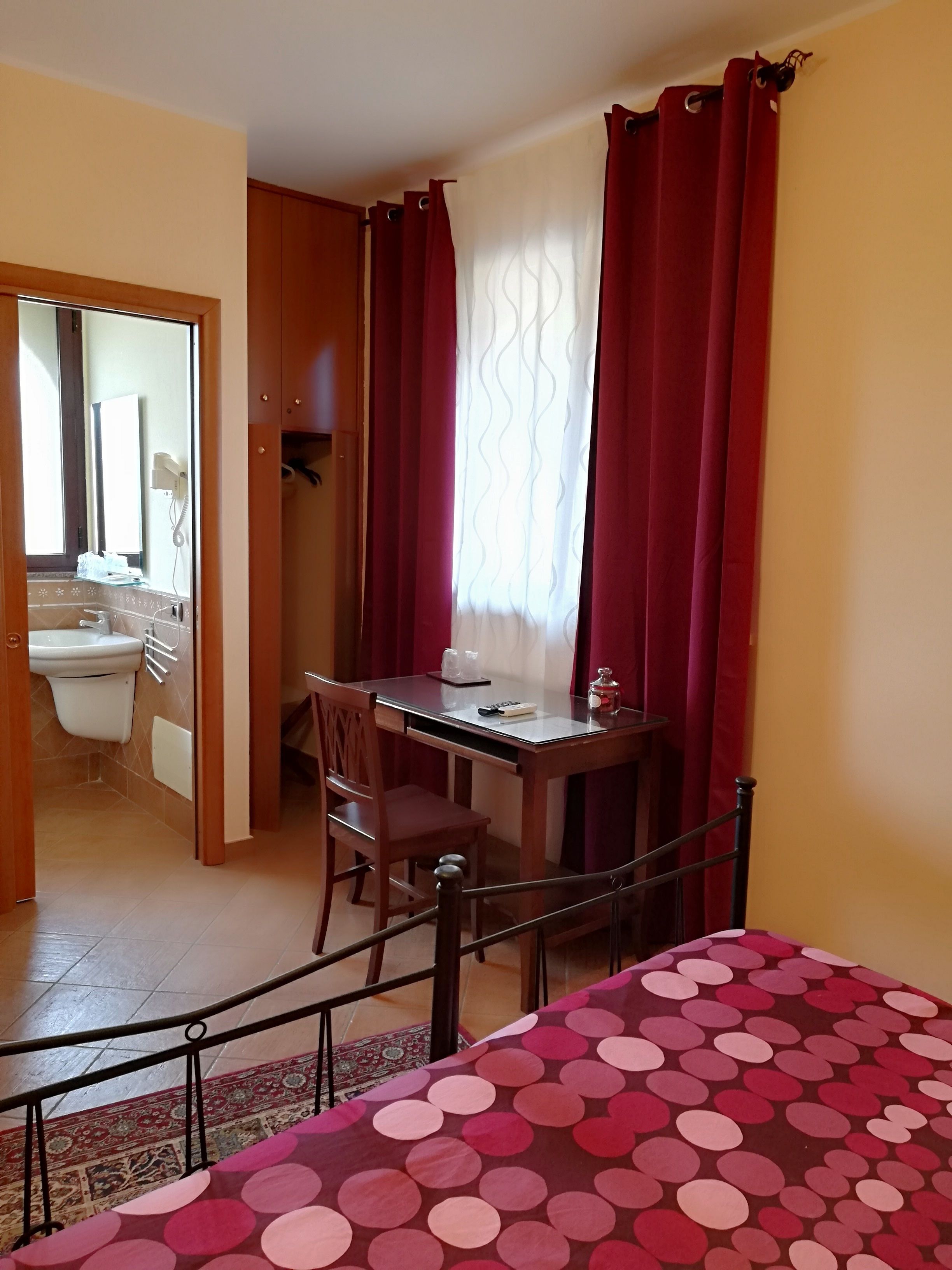 Un dormitorio con cama, escritorio y silla. Se ve un baño por una puerta abierta.