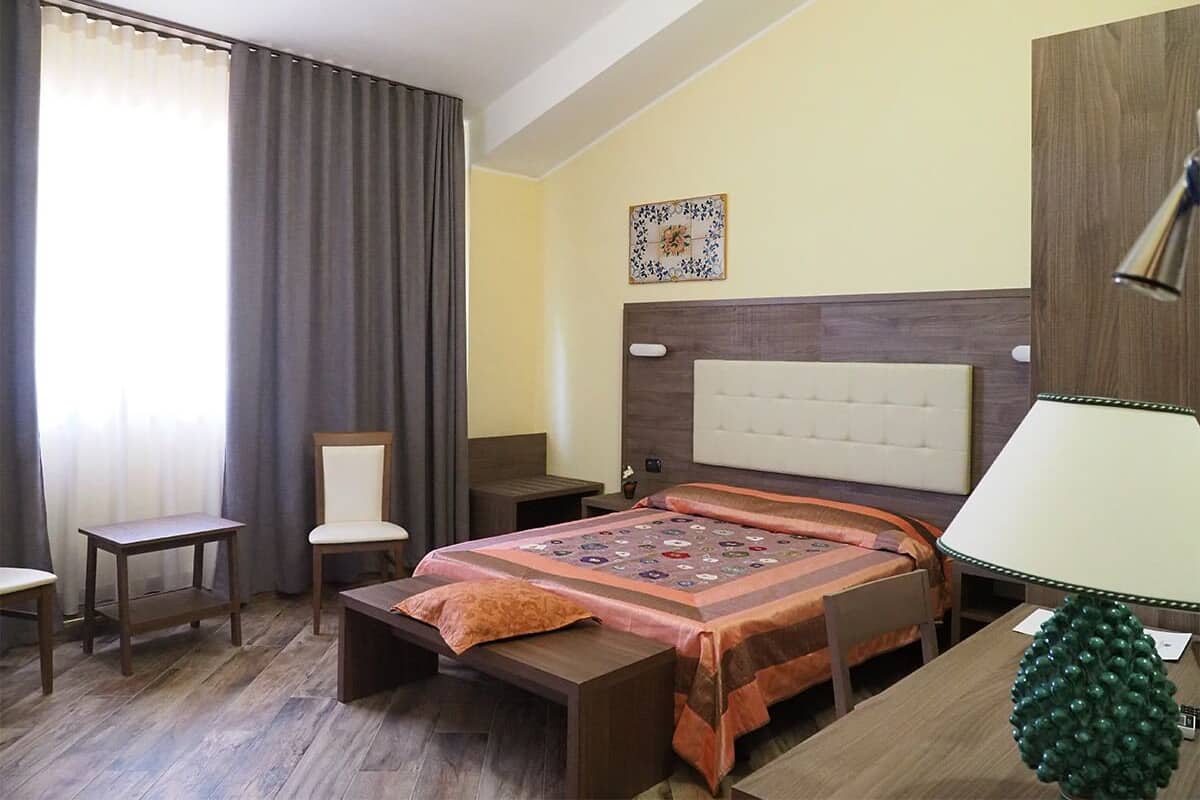 Une chambre d’hôtel comprenant un lit, une table de chevet, une chaise, un bureau et une lampe.