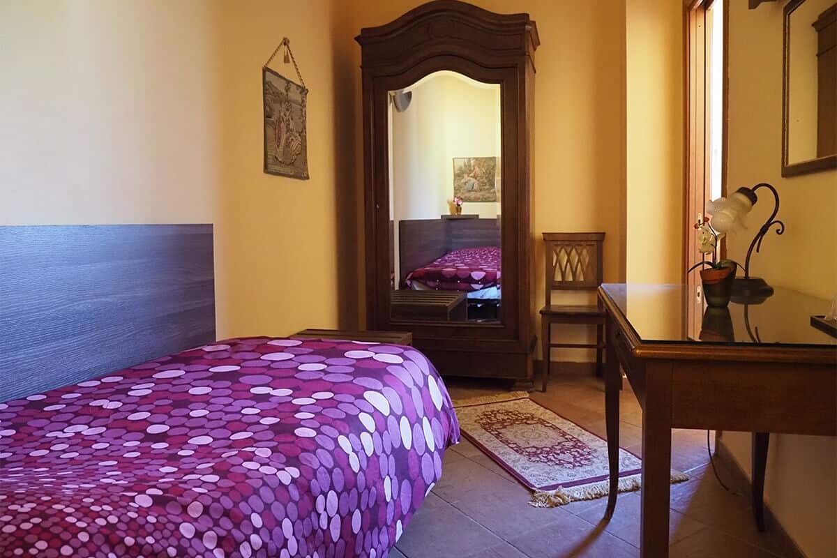 Une chambre à coucher avec un lit, une armoire en bois, une petite table et un miroir.