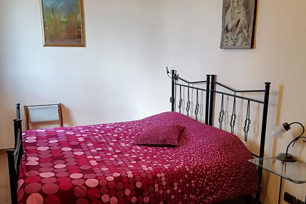 Une chambre à coucher avec un lit, une chaise, un tapis et deux tableaux accrochés aux murs.